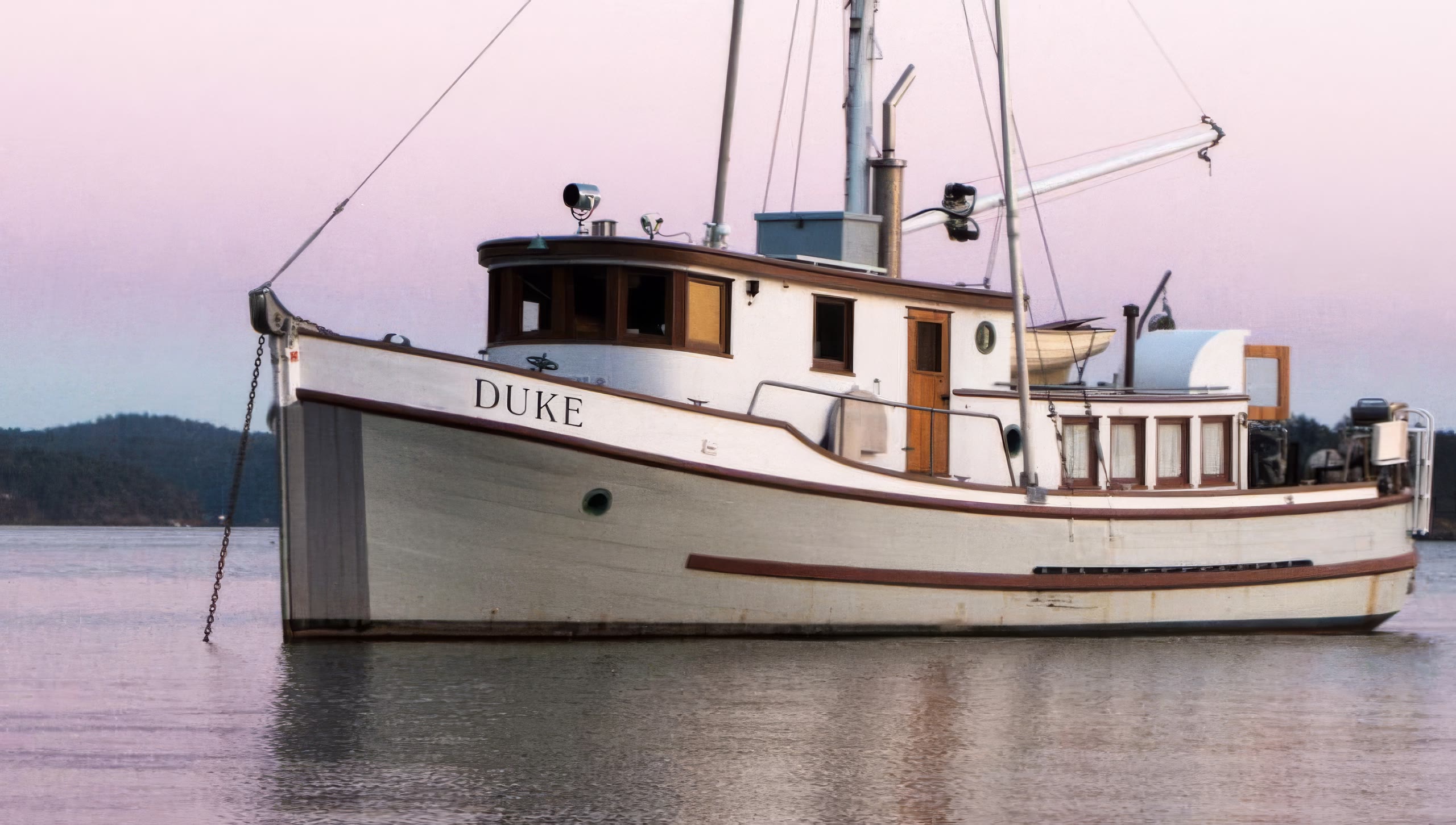 Duke at anchor off Jones Island under a pink dusk sky, showing her wheelhouse and long wooden hull