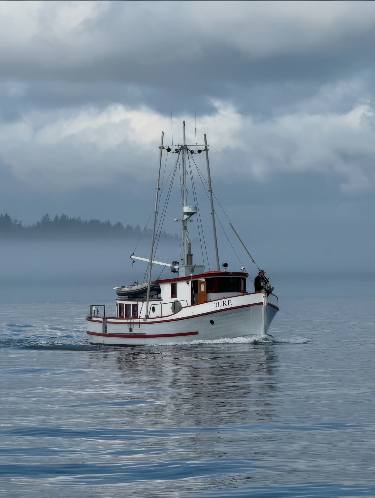 Duke under way through coastal fog, a figure at the rail